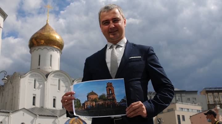 Москвич Павел Осипов позирует на фоне храма Николы Чудотворца у Тверской заставы — мимо этой святыни он ежедневно ходит на работу. В руках у Павла — фото переданного им Белевской епархии храма. Мужчина очень надеется скоро увидеть строение обновленным и готовым принять прихожан