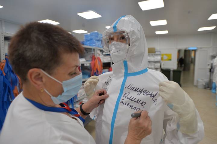 Тот же временный госпиталь на ВДНХ. Медсестра Наталья Казачкина пишет на костюме врача-анестезиолога Алины Манушковой ее имя, фамилию и отчество, чтобы пациенты знали, кто их лечит