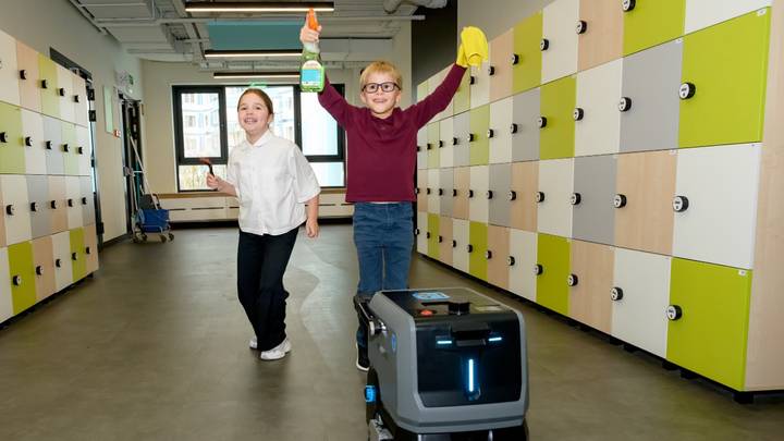 Ученики 2-го класса Варвара Исаева и Артем Чулков рядом с роботом-уборщиком в школе № 1514